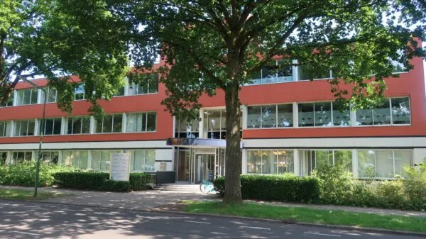 Vooraanzicht van een modern kantoorgebouw aan de Jan van Eycklaan 24, omgeven door groen en schaduwrijke bomen.